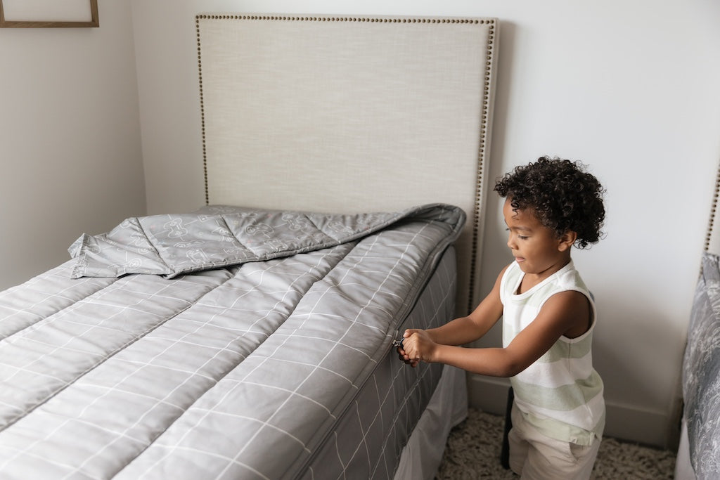 A young boy zipping a set of level up zipper bedding.