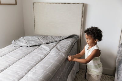 A young boy zipping a set of level up zipper bedding.
