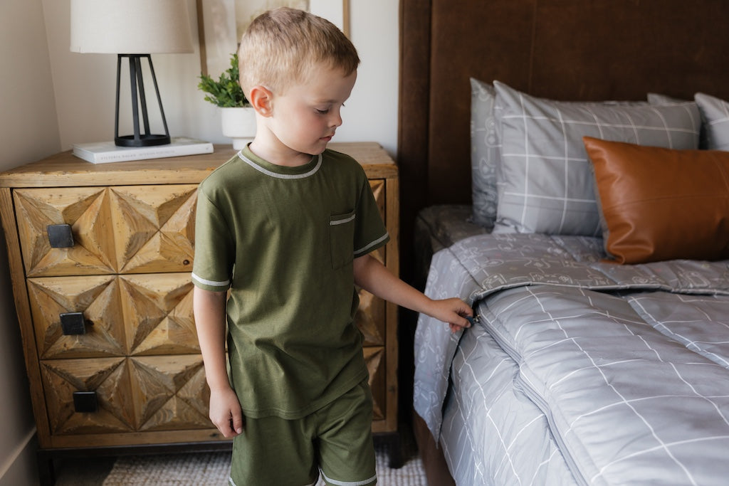 A young boy zipping a set of level up zipper bedding.