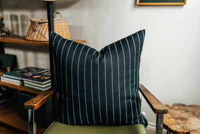 A black striped euro pillow arranged on a green chair.