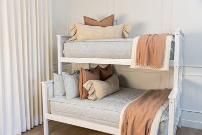 A bunk bed made with light blue floral embossed zipper bedding with cream and terracotta accessories
