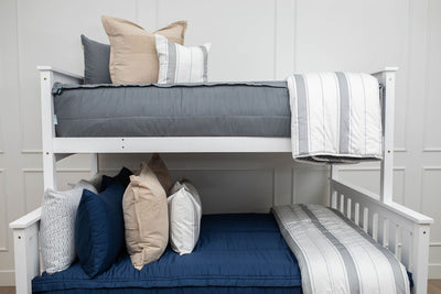 A standard bunk bed with both bunks made with zipper bedding, one gray and navy blue and neutral and gray striped pillows and blankets.