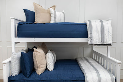 A standard bunk bed with both bunks made with navy blue zipper bedding and neutral and gray striped pillows and blankets.