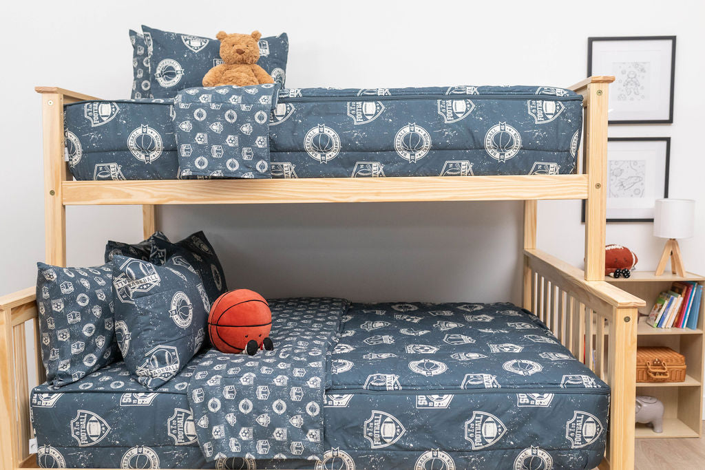 A bunk bed where both bunks are made with blue sports themed kids zipper bedding