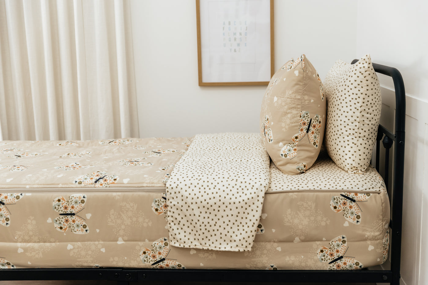 A bed made with butterfly printed zipper bedding, showcasing the pillowcase and sham and the top of the bedding turned down to show the inside lining.