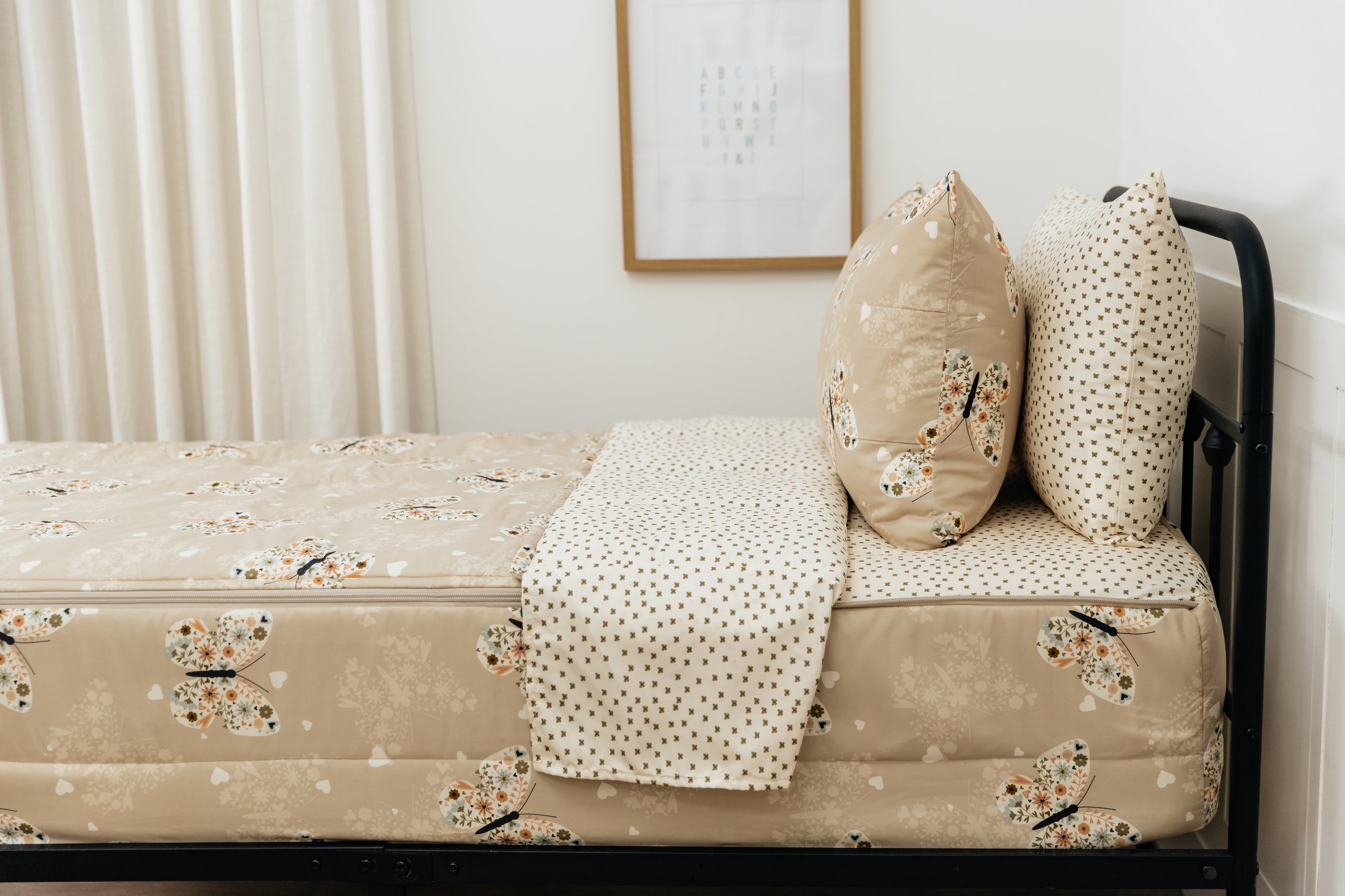A bed made with butterfly printed zipper bedding, showcasing the pillowcase and sham and the top of the bedding turned down to show the inside lining.