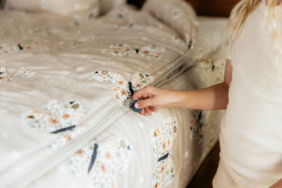 A tight shot of a girl pulling the zipper on a set of butterfly printed zipper bedding.