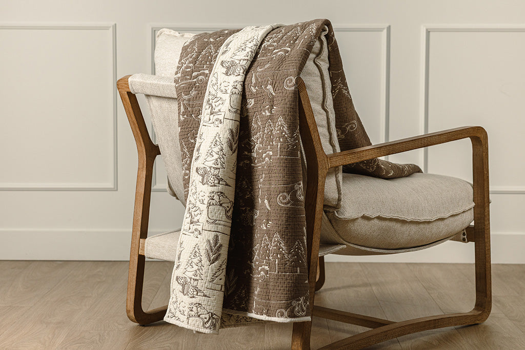 A cream and brown quilted blanket on a chair.