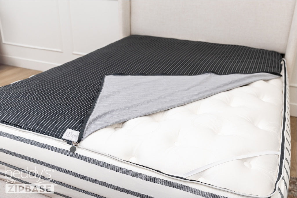 A ZipBase sheet partially unzipped and pulled back to show how it detaches from the rest of the base sheet wrapped around the sides of the mattress.