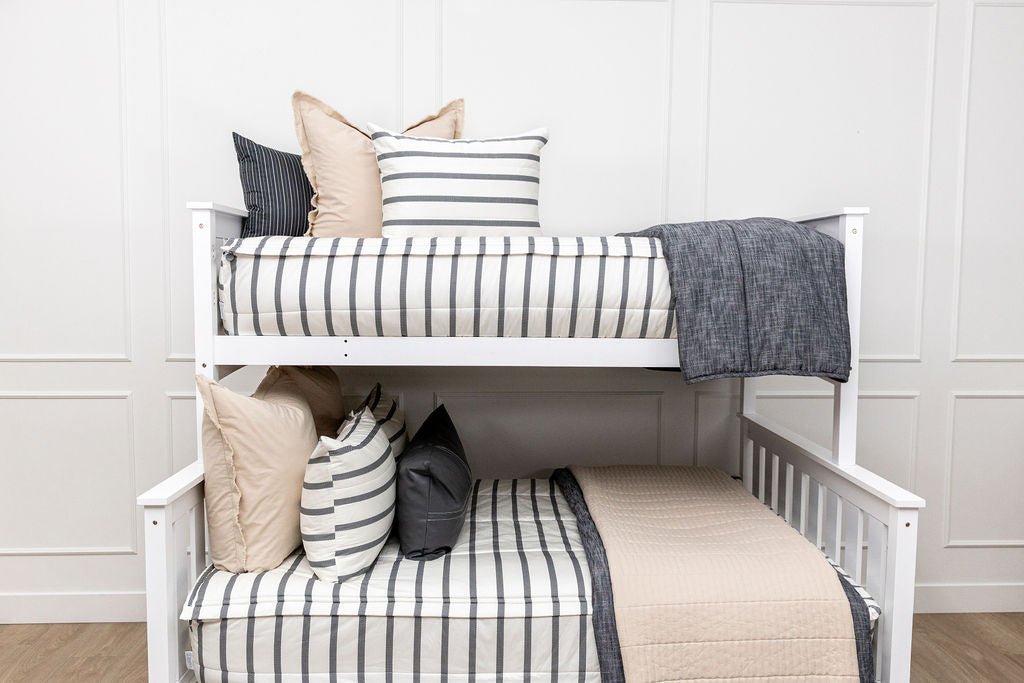 A bunk bed made with white and black striped zipper bedding and an assortment of tan and black accessories.