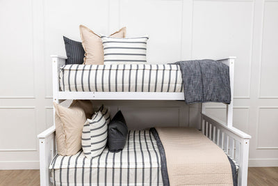 A bunk bed made with white and black striped zipper bedding and an assortment of tan and black accessories.
