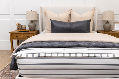 A queen bed made with white and black striped zipper bedding paired with neutral and black accessories.