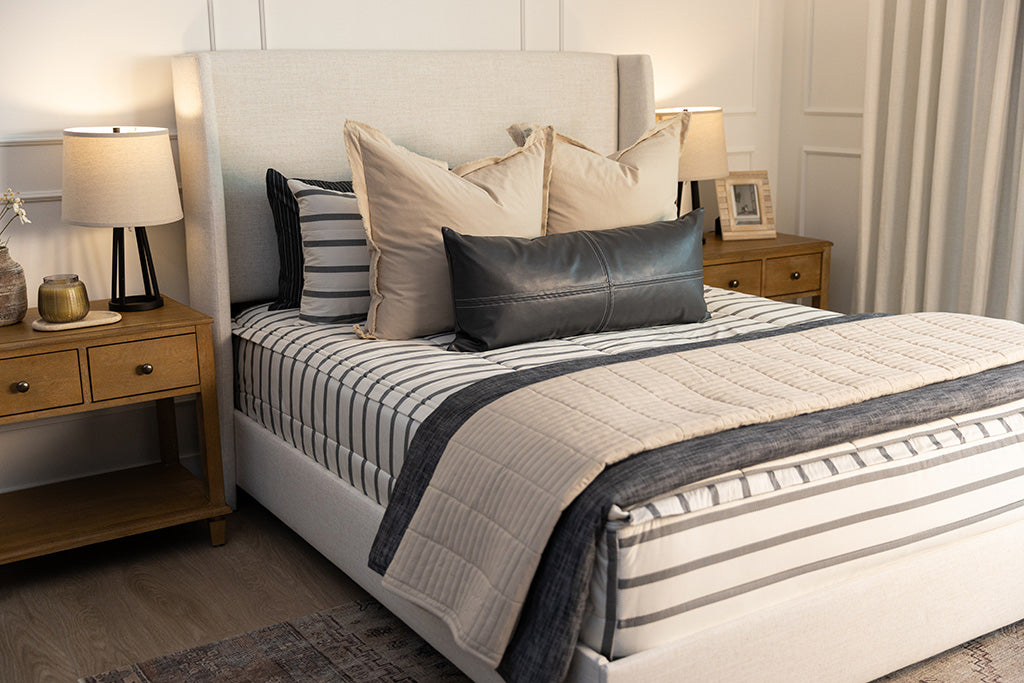 A queen bed made with white and black striped zipper bedding paired with neutral and black accessories.