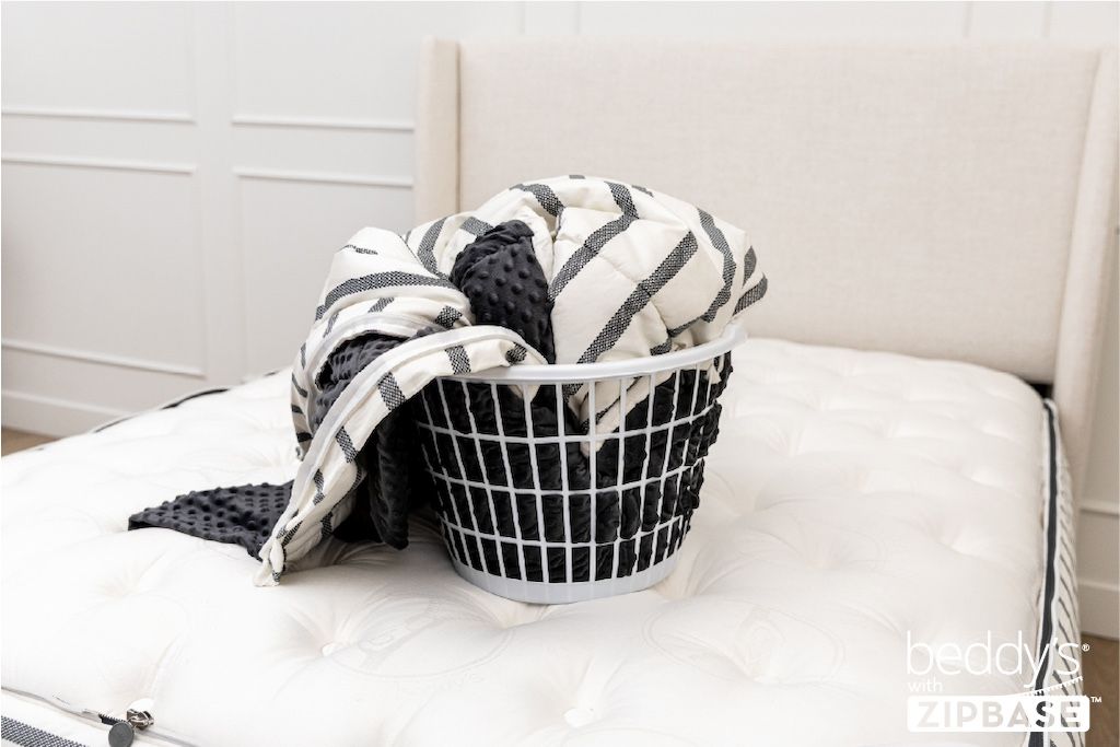 The ZipBase sheet and top comforter portion removed and sitting in a basket on top of a bed