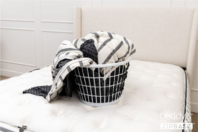 The ZipBase sheet and top comforter portion removed and sitting in a basket on top of a bed