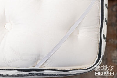 A close up shot of a zipper bedding set with ZipBase with the inside sheet unzipped and pulled back to reveal the elastic.