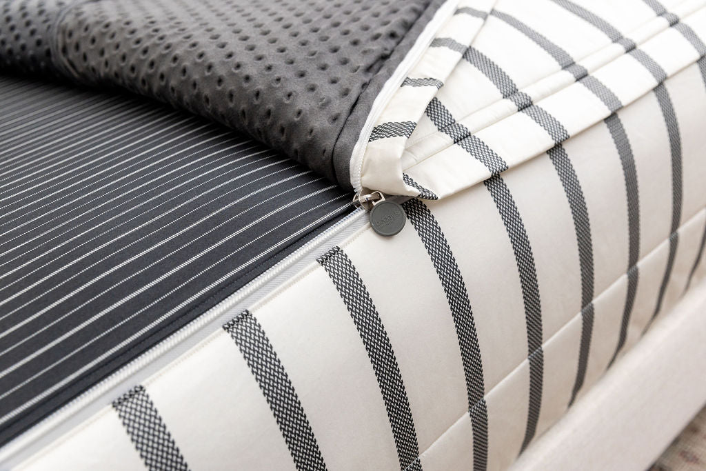A close up view of the zipper function on white and black striped zipper bedding.