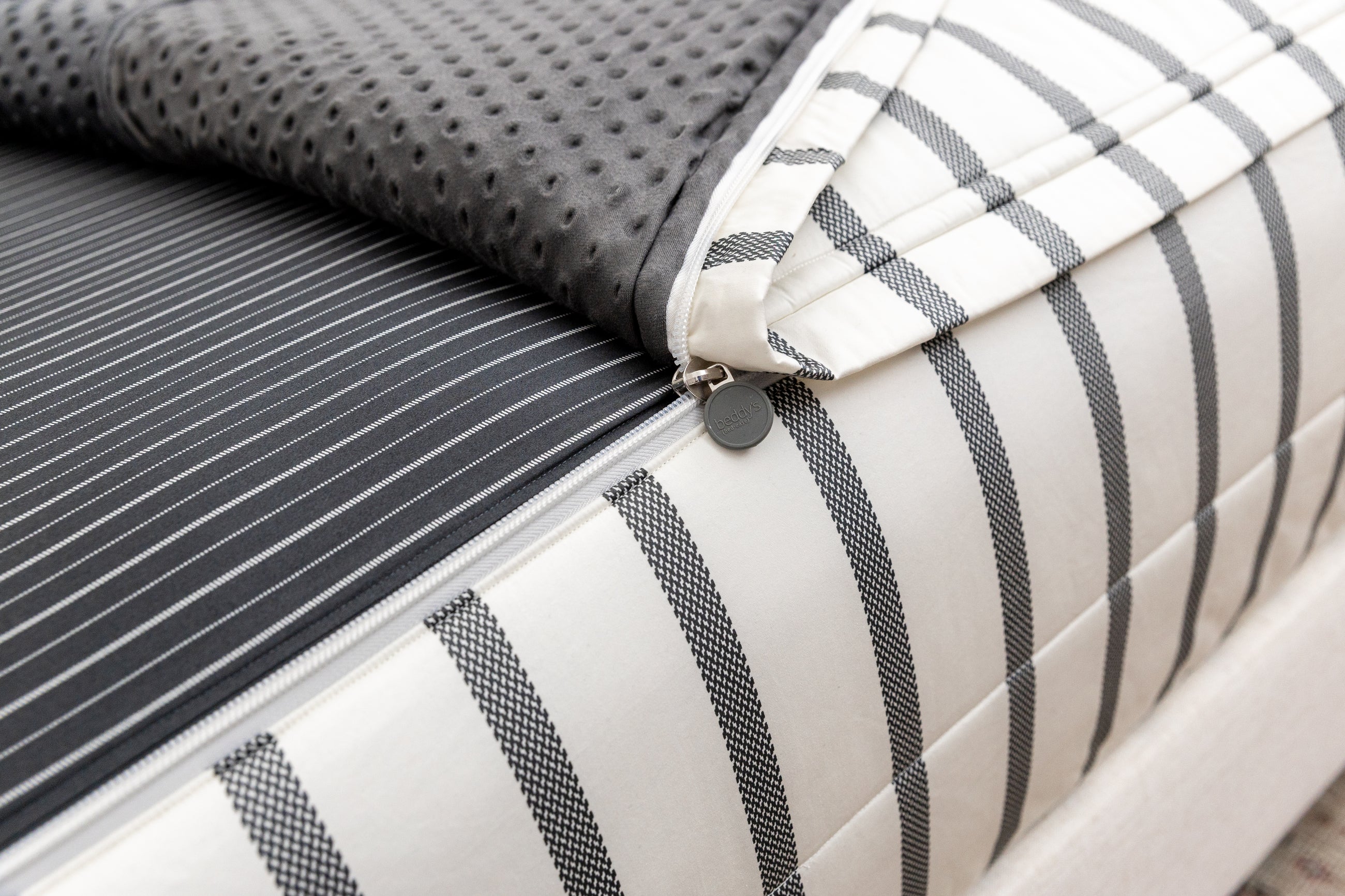 A close up view of the zipper feature on a set of white and black striped zipper bedding.