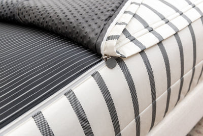 A close up view of the zipper feature on a set of white and black striped zipper bedding.