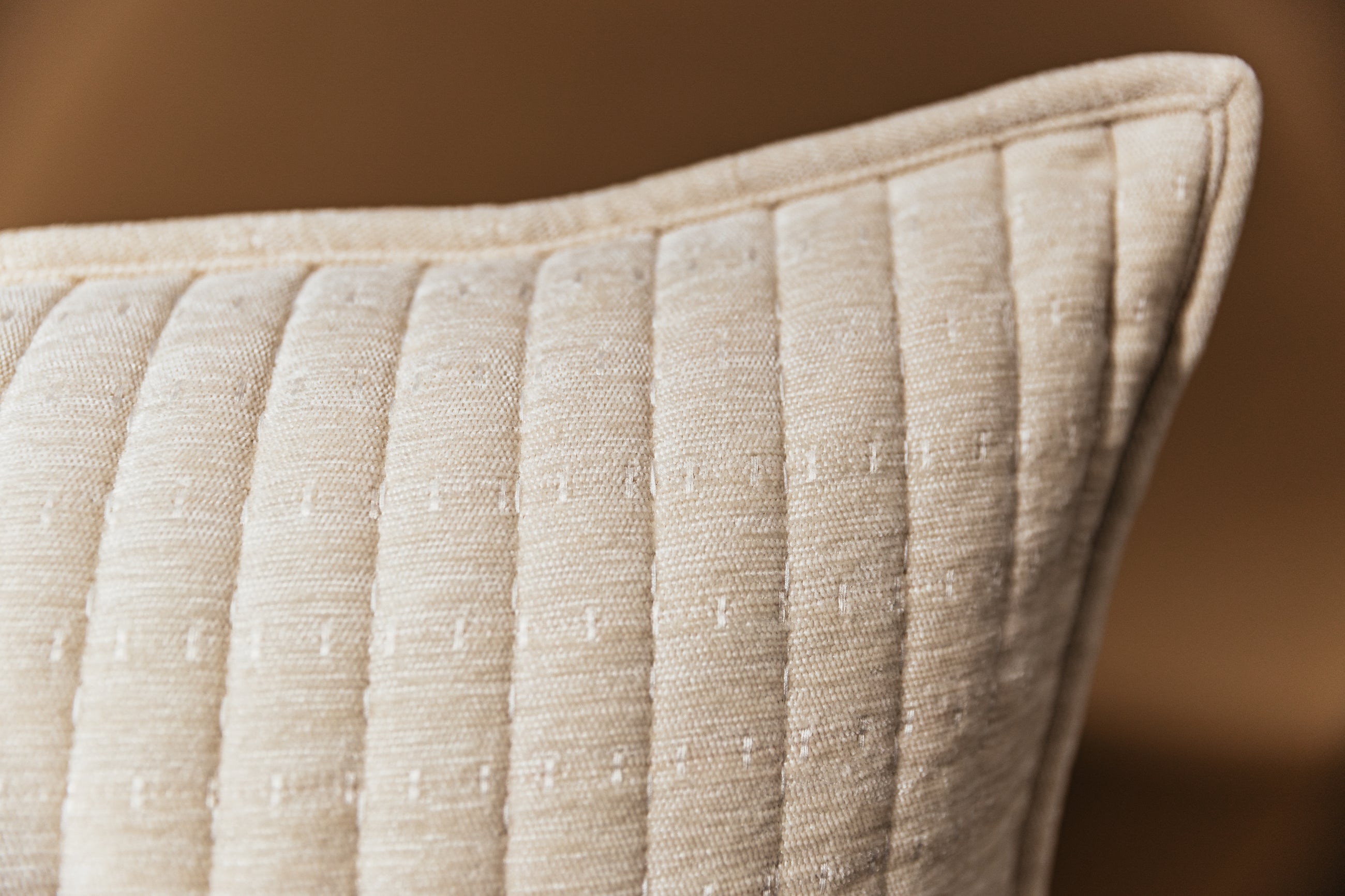 Corner shot of cream euro pillow on tan background