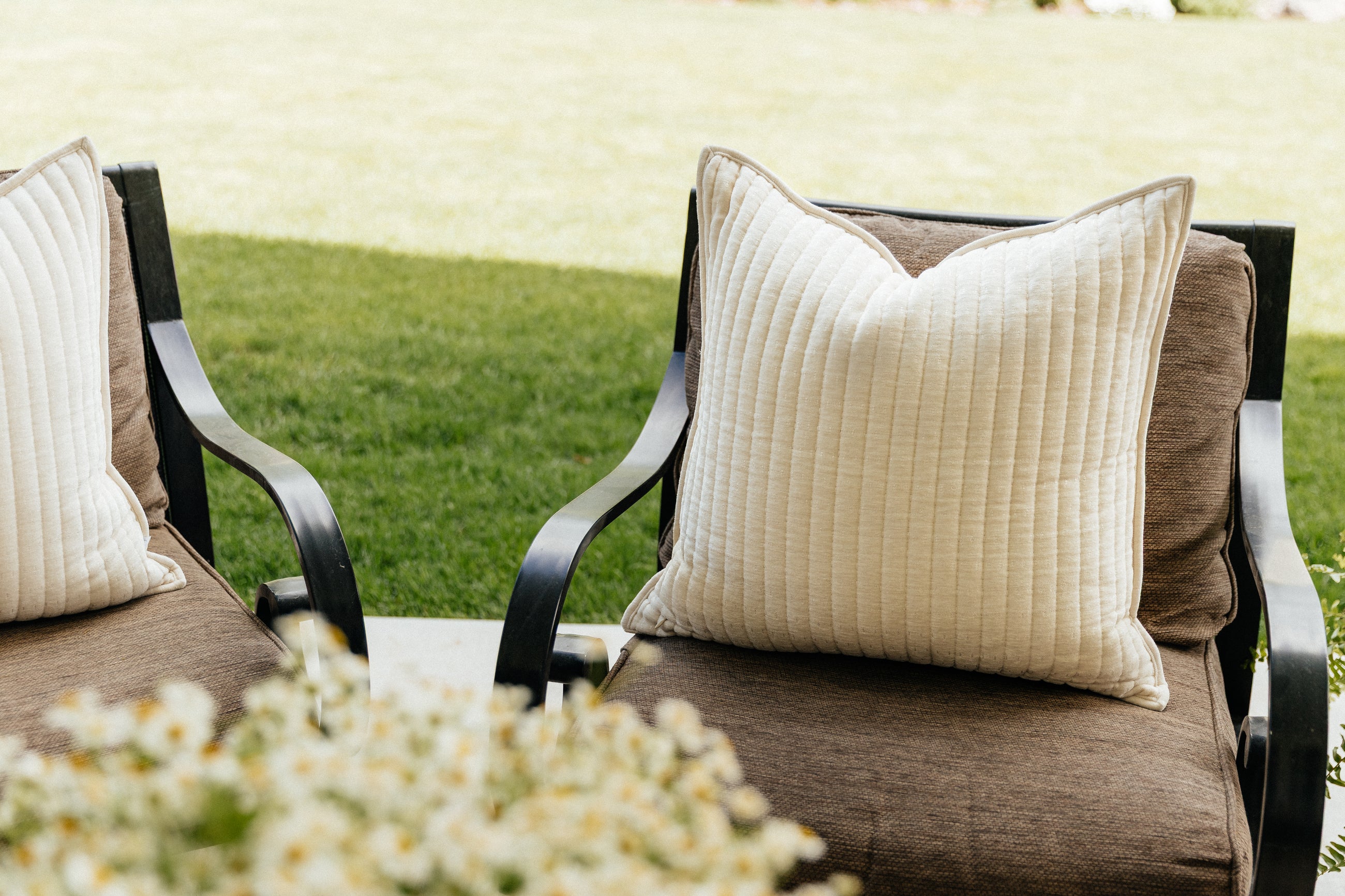 Cream textured pillow outside on a brown chair