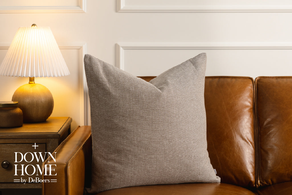 A brown woven pillow on a leather couch.