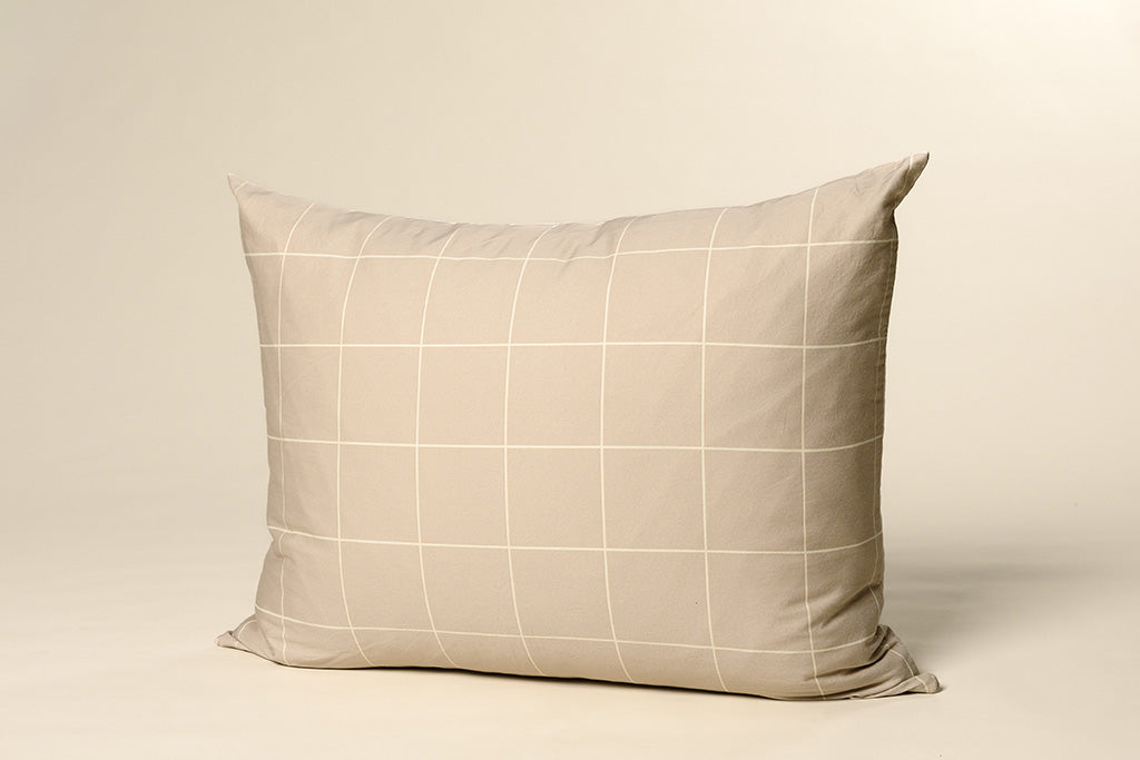 A tan and white grid printed pillowcase on a cream backdrop.