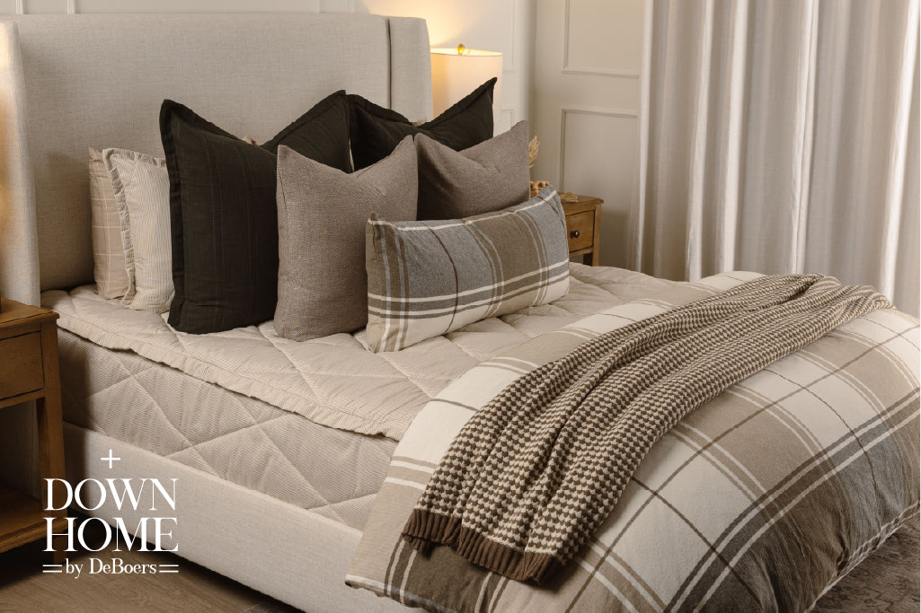 Striped, quilted, tan zipper bedding with black, brown, plaid, and knitted accessories. 