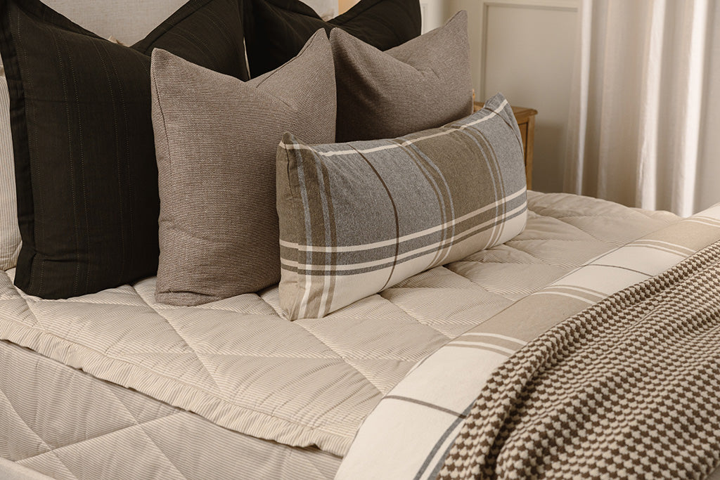 A close up photo of tan, striped, quilted zipper bedding.