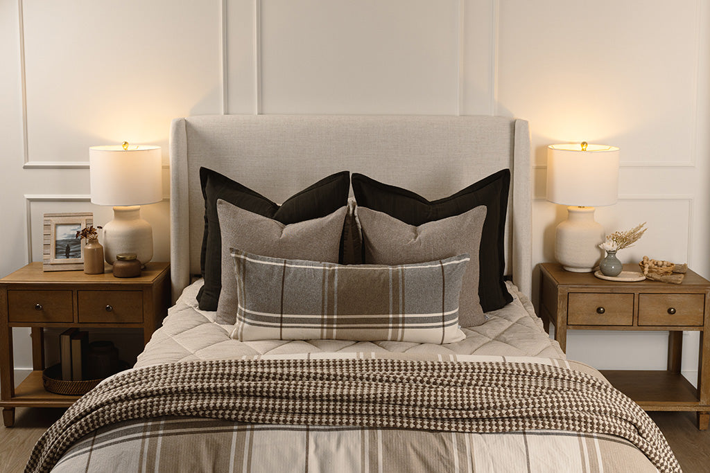 Tan stripe quilted bedding with black, brown, plaid, and knit accessories. 
