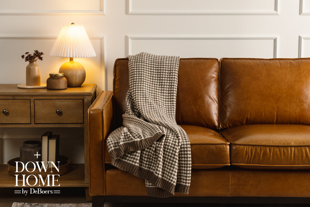 A brown and cream scallop weave throw on an orange leather couch.