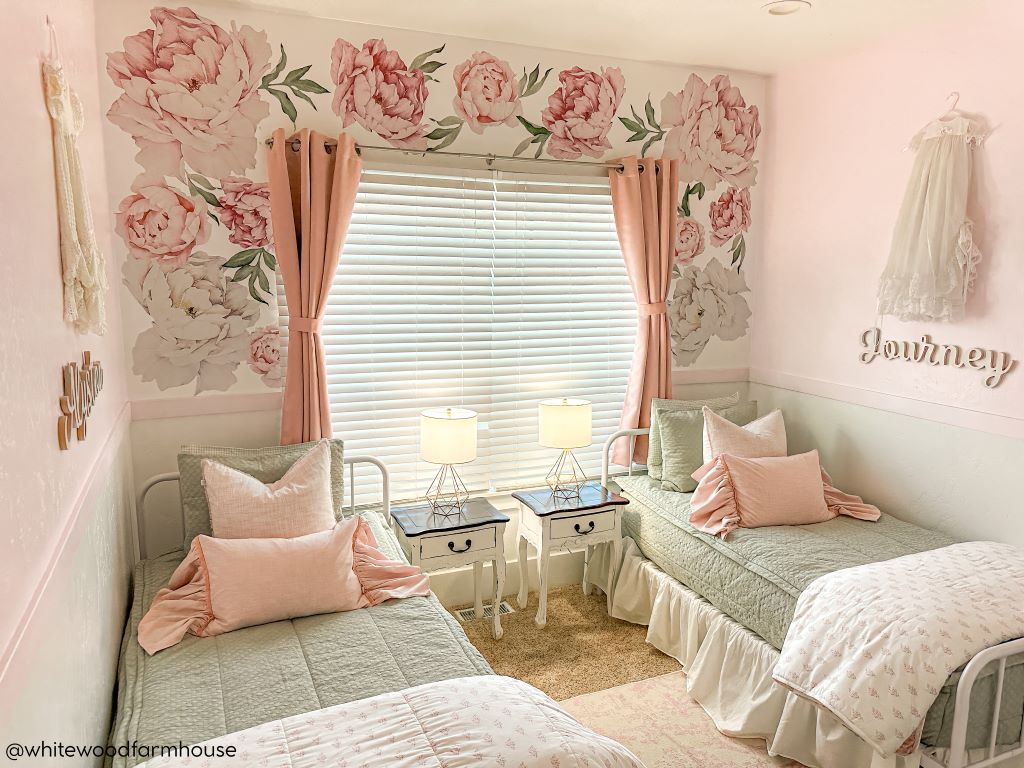 Two twin beds made with sage green zipper bedding and adorned with light pink pillows and matching floral blankets.