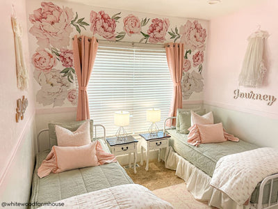 Two twin beds made with sage green zipper bedding and adorned with light pink pillows and matching floral blankets.