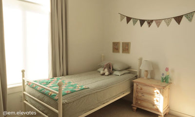 A twin bed in a brightly lit bedroom made with soft green zipper bedding .