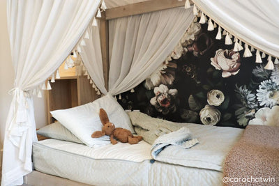 A twin canopy bed made with soft green zipper bedding with the top comforter unzipped and a tan fuzzy blanket at the end of the bed.