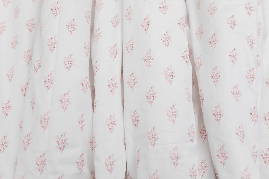 A close up of a pink floral pattern white blanket. 