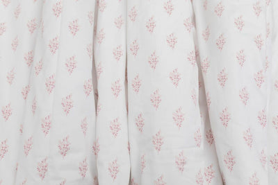 A close up of a pink floral pattern white blanket. 