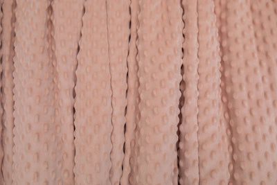 A close up of a softly textured dusty rose pink minky blanket.