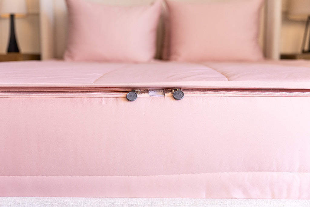 End of bed showing double zippers on pink zipper bedding.