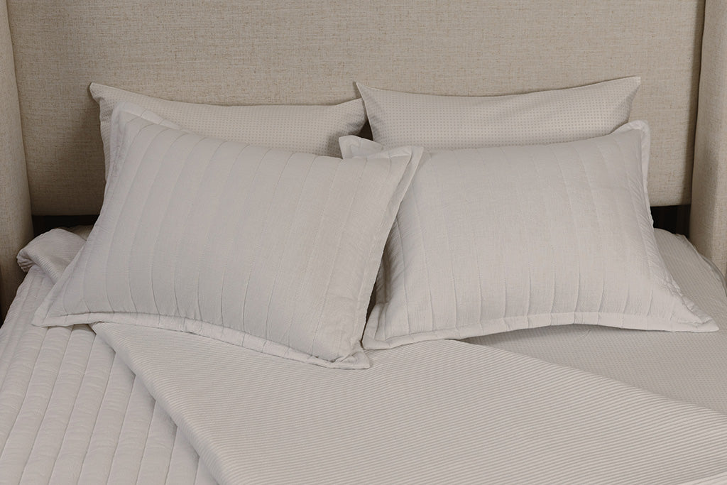 Overhead photo of white stripe quilted zipper bedding with white and tan crossed bed sheets and white corduroy minky interior.