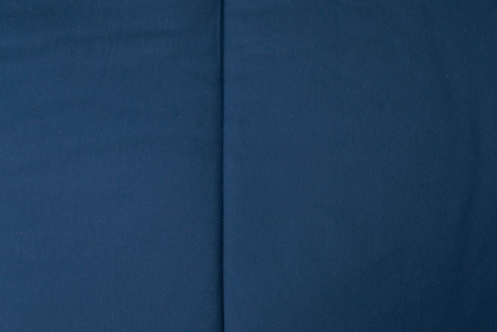A close up detailed view of the exterior of a bed made with navy blue zipper bedding.
