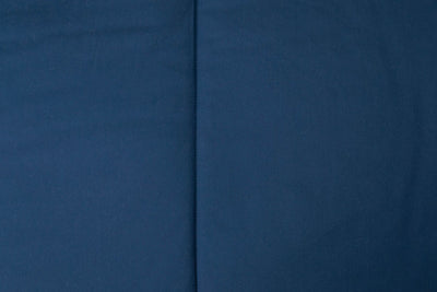 A close up detailed view of the exterior of a bed made with navy blue zipper bedding.