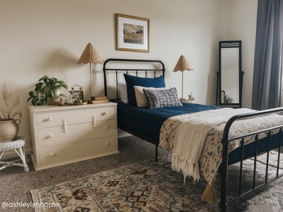 A twin bed made with navy blue zipper bedding and an assortment of neutral pattern pillows and blankets.