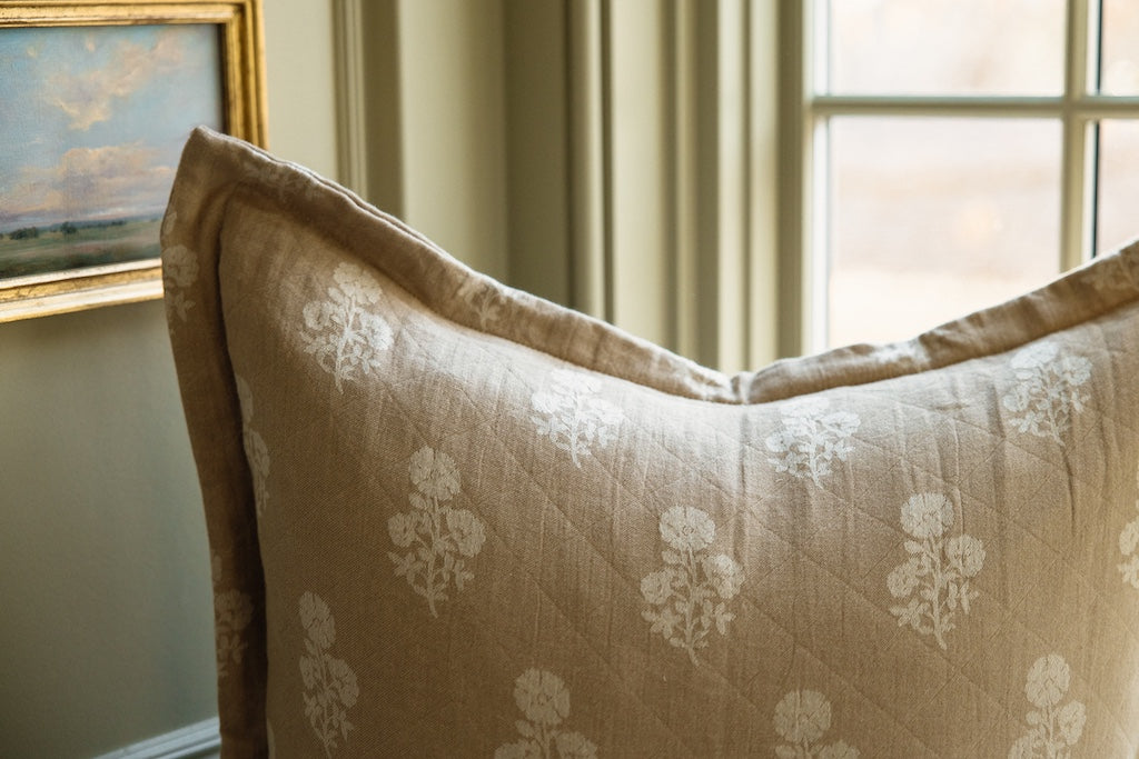 A tan and white floral pillow.