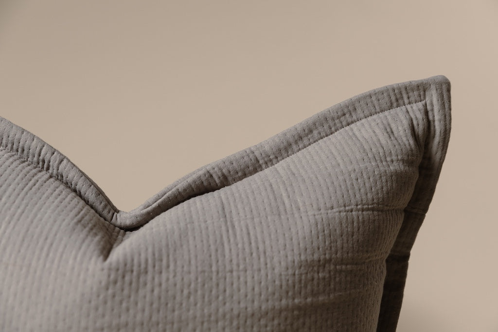 A gray stitched XL pillow on a cream backdrop.