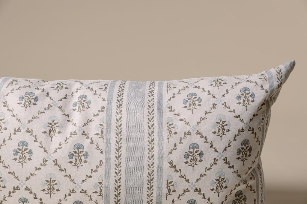 A blue floral lumbar pillow on a cream backdrop.