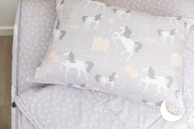 A twin bed made with purple unicorn kids zipper bedding, the top unzipped and slightly pulled back and a pillow on the bed.
