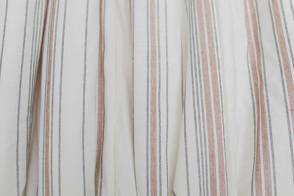 A close up of a white blanket with black and cognac striped pattern design.