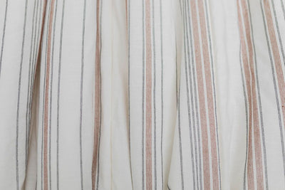 A close up of a white blanket with black and cognac striped pattern design.