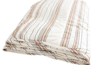 A folded white blanket with black and cognac striped pattern design.